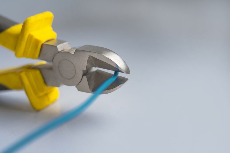 pliers cutting a blue wire in a close up shot showing the shearing action of a cutter