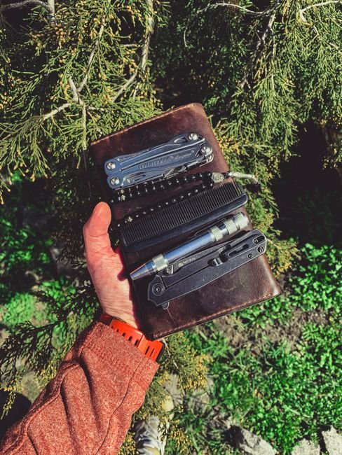 person holding a multitool leather case outdoors