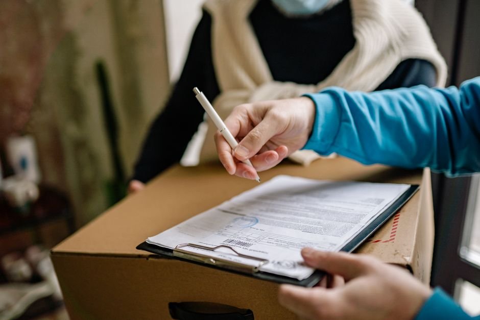 person signing a delivery document on top of a package
