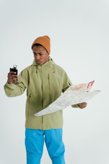 hiker reviewing a paper map alongside a handheld gps device before a trip
