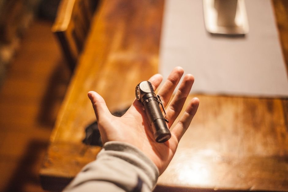 close up of a hand holding a flashlight on a wooden table