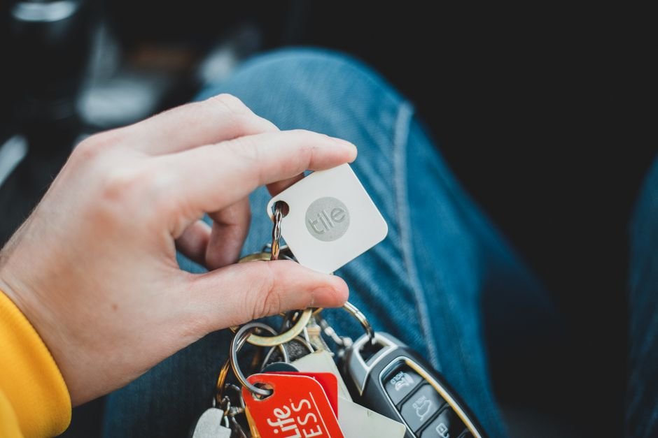 a hand holding a set of keys with various keychains and tags attached