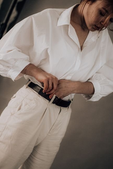 black leather belt threaded through the waistband of tailored trousers