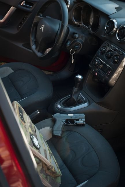 handgun resting on a car seat next to keys illustrating the risk of casual vehicle storage
