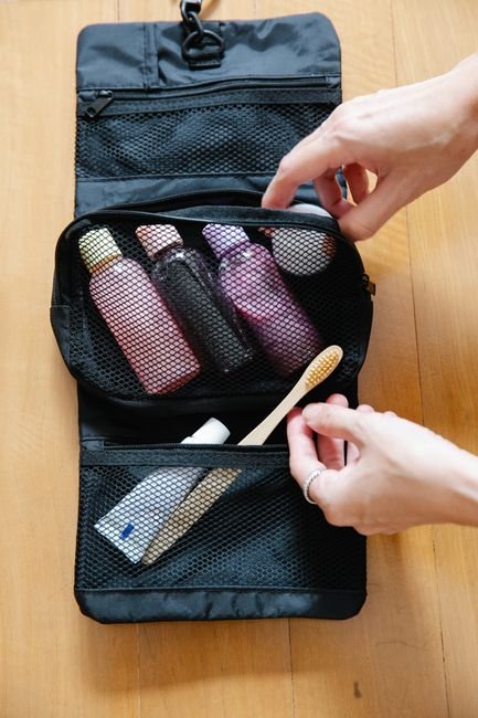 an open toiletry bag with bottles and a toothbrush laid out on a wooden surface