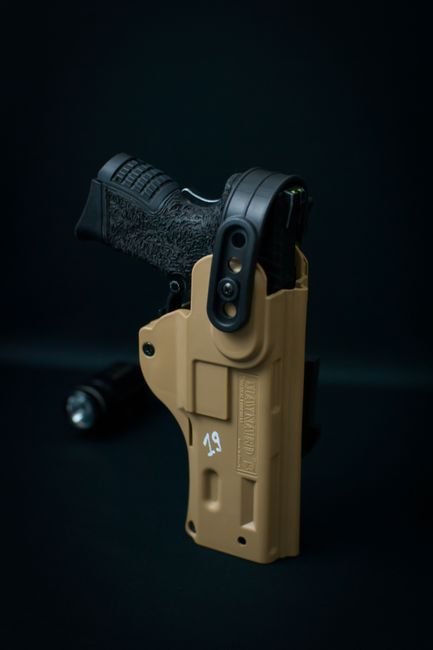 pexels9229937 edc deals a black handgun secured in a tan holster
