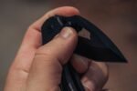 hand gripping an open folding knife edge presented for cutting