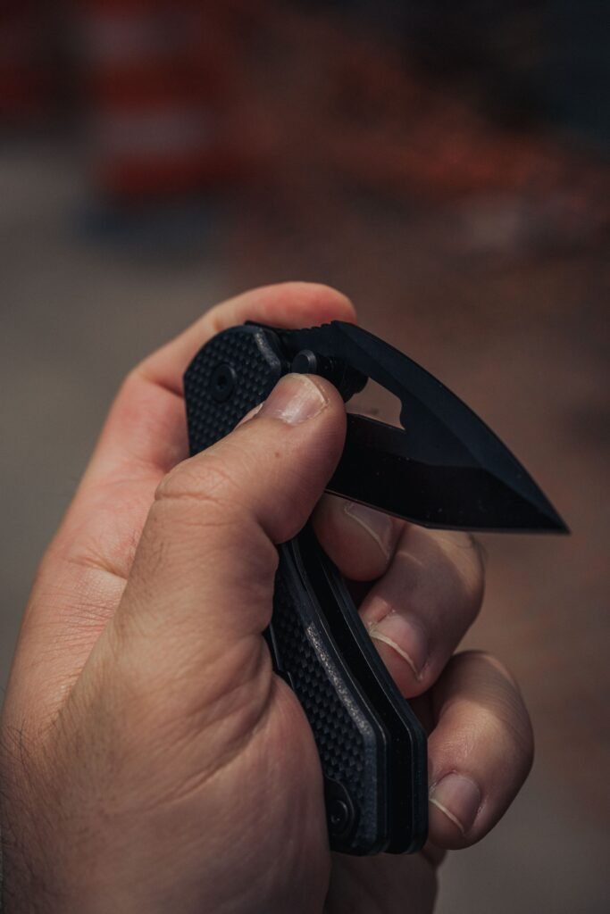hand gripping an open folding knife edge presented for cutting