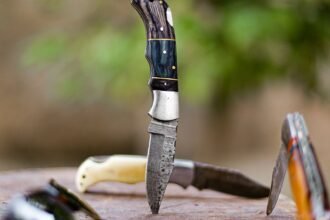 several knives with ornate handles stand upright in a weathered wooden surface outdoors with a blurred green background