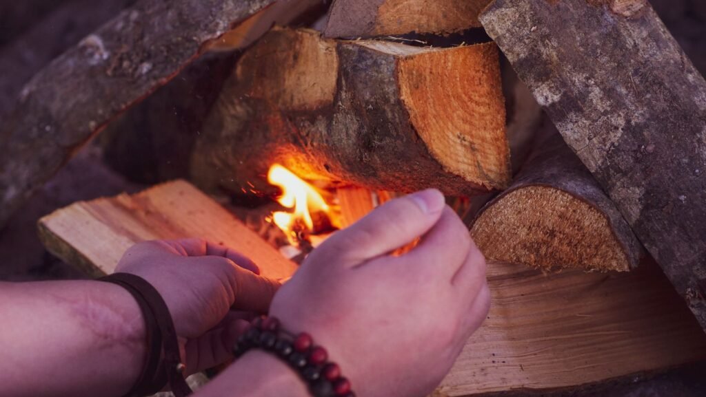hands feeding tinder into a small fire being coaxed alight