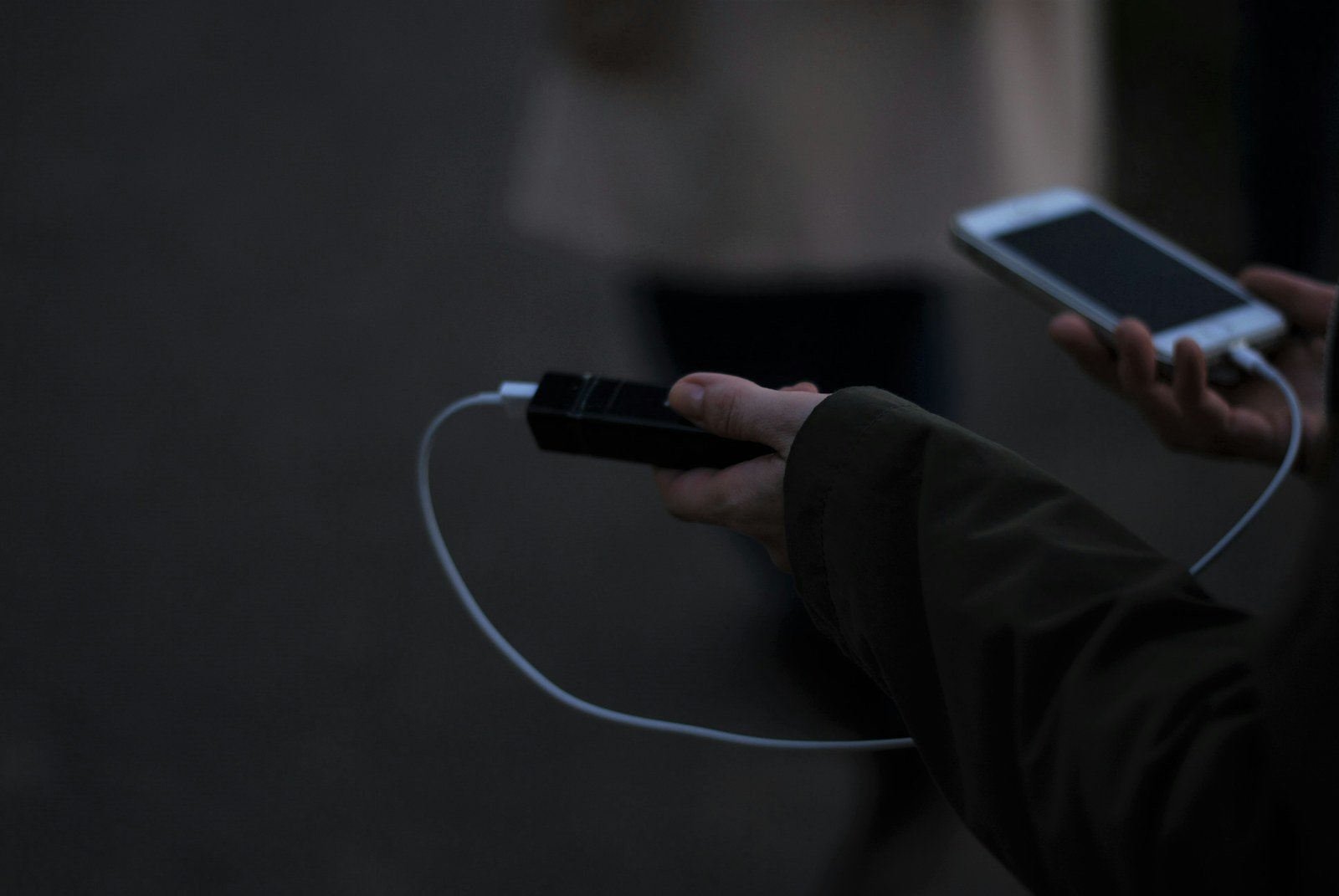 person holding a phone connected to a short charging cable and power bank