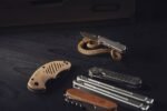 several multitools and a knife laid out on a dark wooden surface
