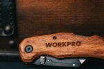 a folding multitool with a wooden handle opened to show its implements
