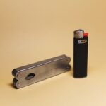 a metal multitool and a lighter arranged flat on a plain background