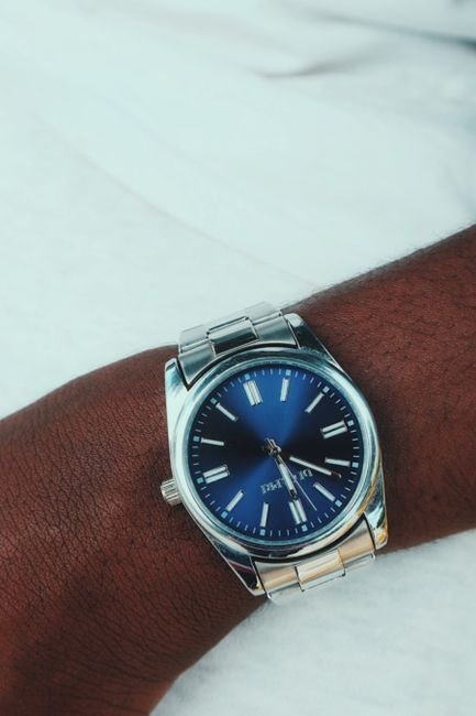 a silver wristwatch with a blue dial worn on the wrist
